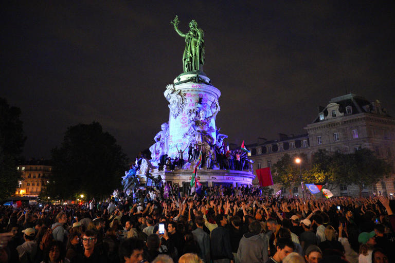 Demonstrators climb on the Monument a la Republique during a protest following the legislative election results in France (Getty Images)