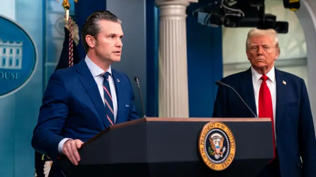 Trump and Hegseth stand at a podium in the white house briefing room. Trump and Hegseth stand at a podium in the white house briefing room.