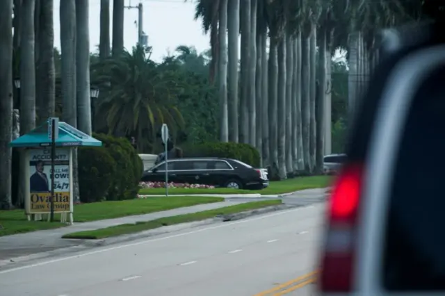 A vehicle drives on a road in Florida, with palm trees in view. A vehicle drives on a road in Florida, with palm trees in view.